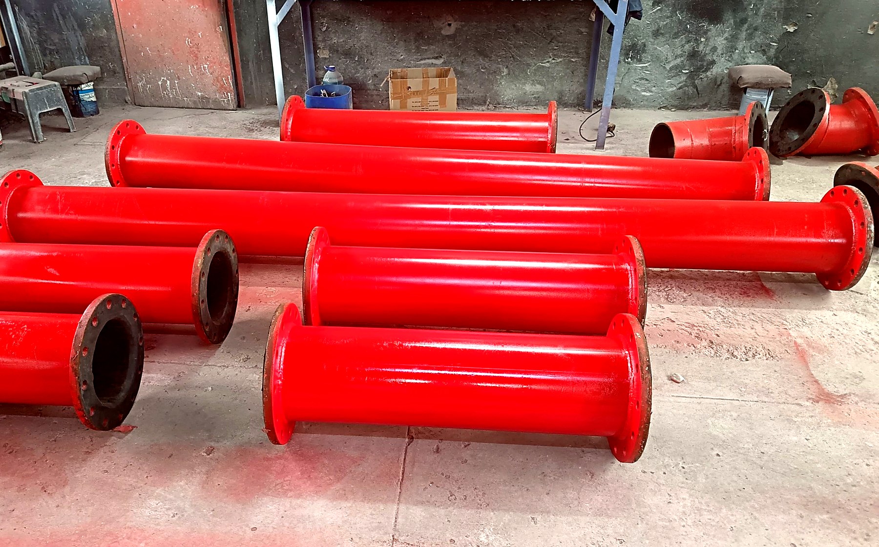 Completed rubber-lined pipe spools laid out on the workshop floor